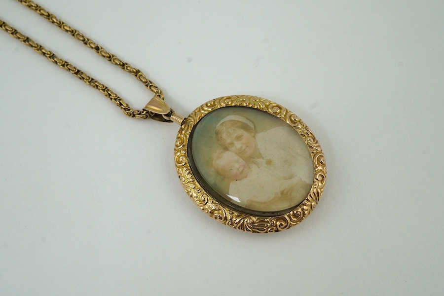 A George V embossed 9ct gold double portrait pendant, 44mm, on a 9ct chain, 37cm, gross weight 30.8 grams. Condition - poor to fair